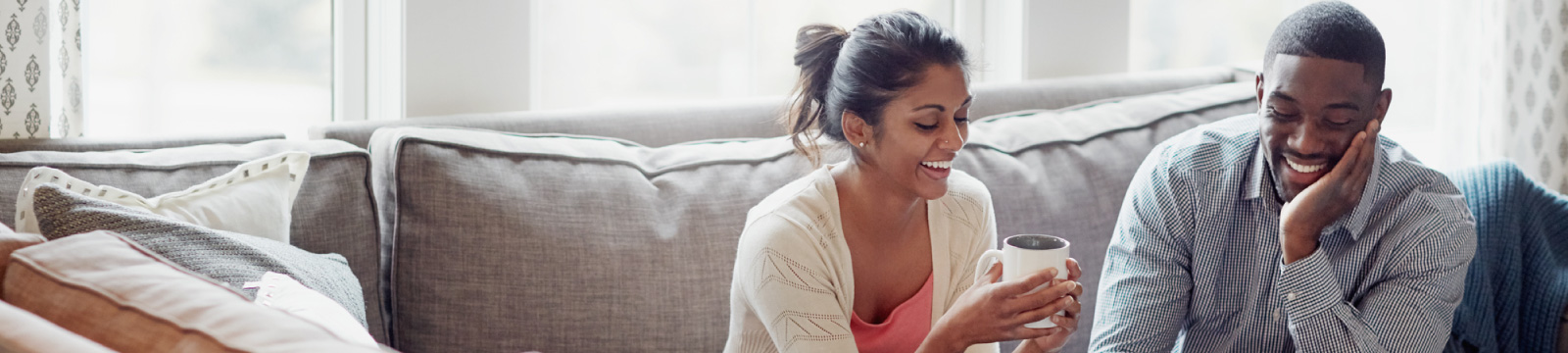 Smiling couple with coffee in living room